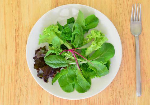 Fresh baby greens in a salad on wood table