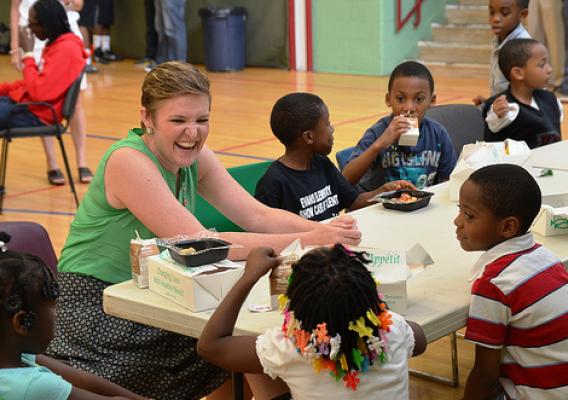 USDA Center for Faith-Based and Neighborhood Partnerships Director Norah Deluhery eating lunch with kids at a Philadelphia Archdiocese’s Nutritional Development Services (NDS) summer food service site.